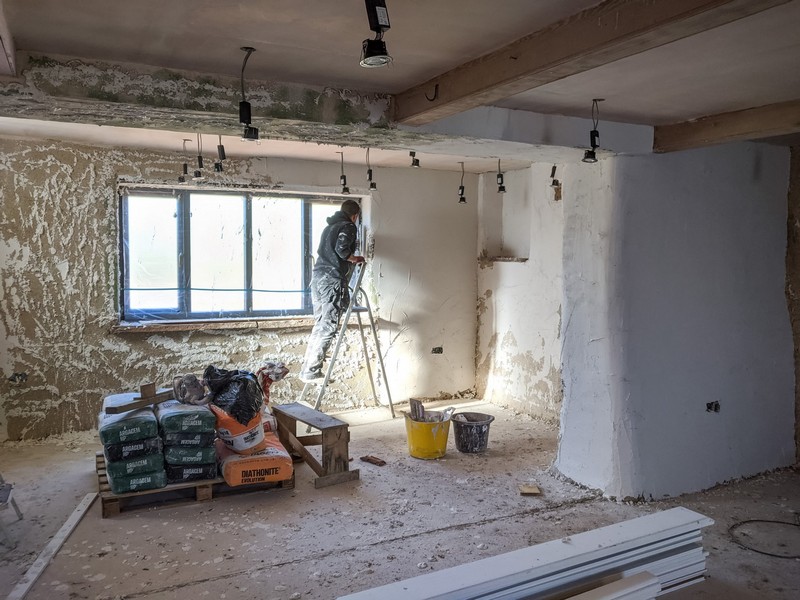 A man applying the lime skin coat to the interior walls