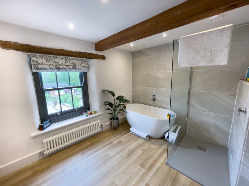 The finished bathroom featuring standalone bath and walk in shower. The roof has wooden beams exposed and the walls are finished with diathonite and argatherm